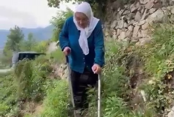 Patika yoldan koltuk değnekleri ile yürüyor